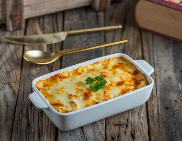 Maccheroni besciamella serviti in un piatto isolato su sfondo di legno vista laterale della pasta