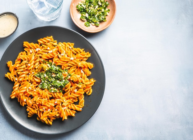 Maccheroni di pasta riccia con salsa di pomodoro e gremolata in un piatto rotondo scuro su un tavolo