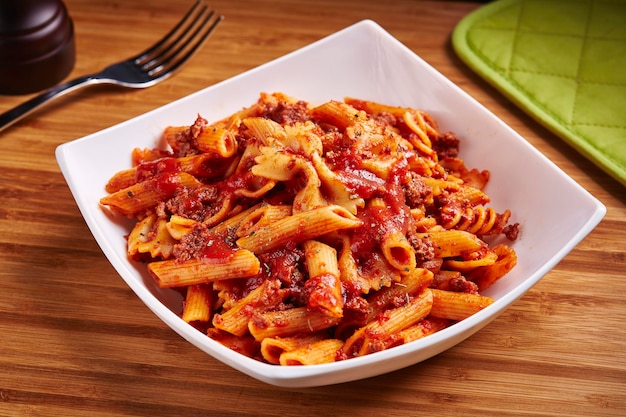 Maccheroni di pollo piccanti di manzo serviti in un piatto isolato sulla vista laterale del tavolo del cibo mediorientale