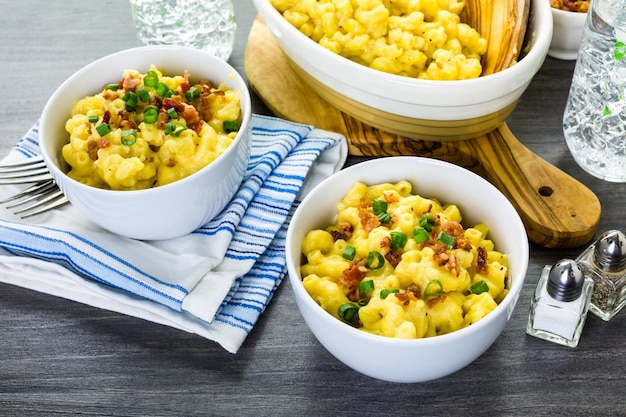 Maccheroni e formaggio guarniti con pezzetti di pancetta ed erba cipollina.