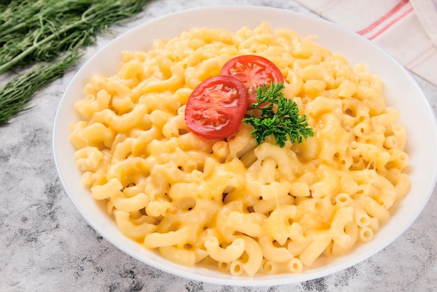 Maccheroni e formaggio su un piatto bianco con prezzemolo e ciliegino