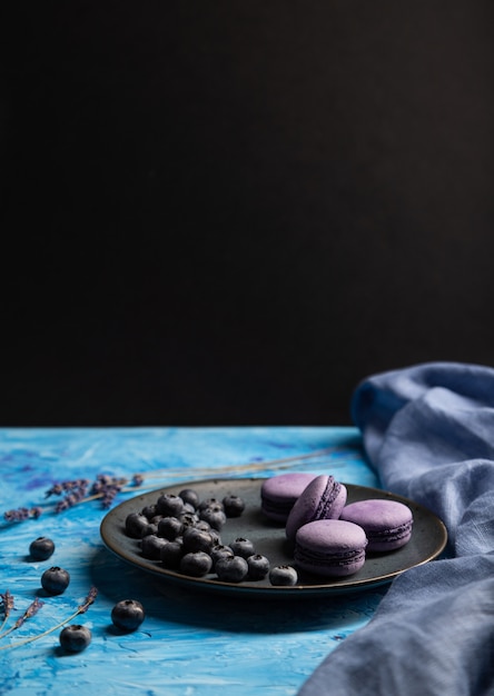 Maccheroni o maccheroni porpora agglutina con i mirtilli sul piatto ceramico su un fondo blu e nero.