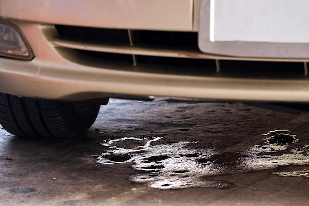 Macchie di olio d'auto gocciolate sul pavimento di cemento mentre l'auto era parcheggiata Il liquido dell'aria condizionata ha gocciolato sul pavimento sotto lo spazio di copia dell'auto