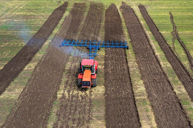 Macchina agricola che raccoglie il raccolto nei campi Il trattore tira un meccanismo per la fienagione La raccolta in autunno al mattino all'alba agroalimentare nella regione di Altai Russia vista aerea dall'alto