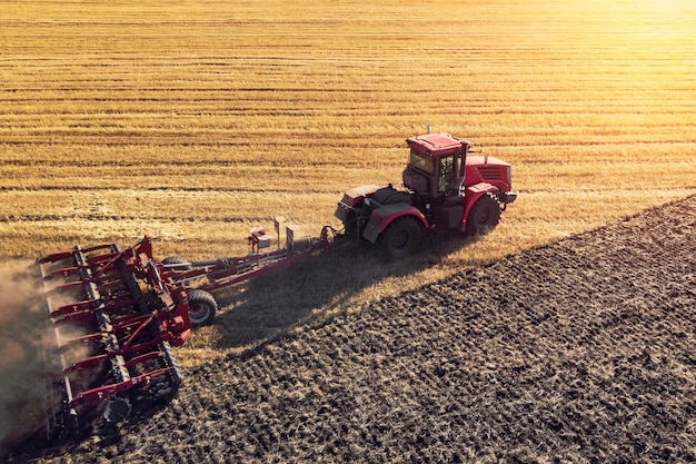 Macchina agricola che raccoglie il raccolto nei campi Il trattore tira un meccanismo per la fienagione La raccolta in autunno al mattino all'alba agroalimentare nella regione di Altai Russia