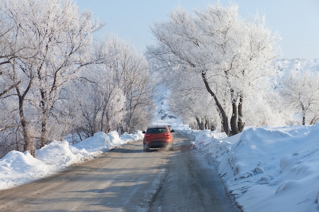 Macchina arancione che si muove su una bellissima strada invernale