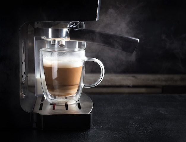 Macchina da caffè con vapore nel processo di preparazione del caffèIl concetto di un servizio di preparazione del caffè