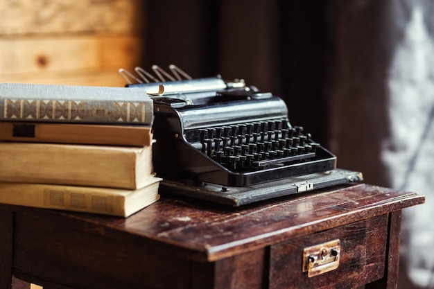 Macchina da scrivere d'epoca e libri sul tavolo con carta bianca sulla scrivania di legno