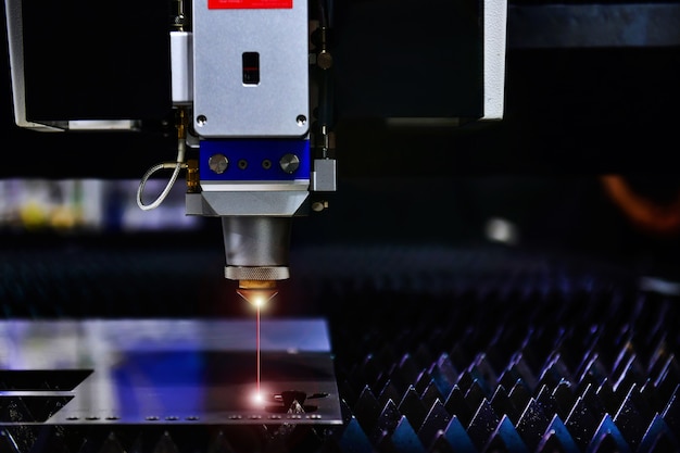 Macchina da taglio laser industriale durante il taglio della lamiera con la luce scintillante