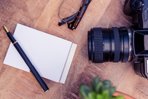 Macchina fotografica a penna e carta sulla tavola di legno in ufficio