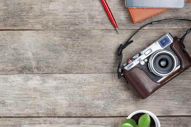 Macchina fotografica classica, con un blocco note marrone, una penna rossa, un telefono e una crescita verde. Elenco di concetti per un fotografo di viaggi