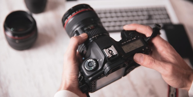 Macchina fotografica della mano dell'uomo del fotografo sulla scrivania