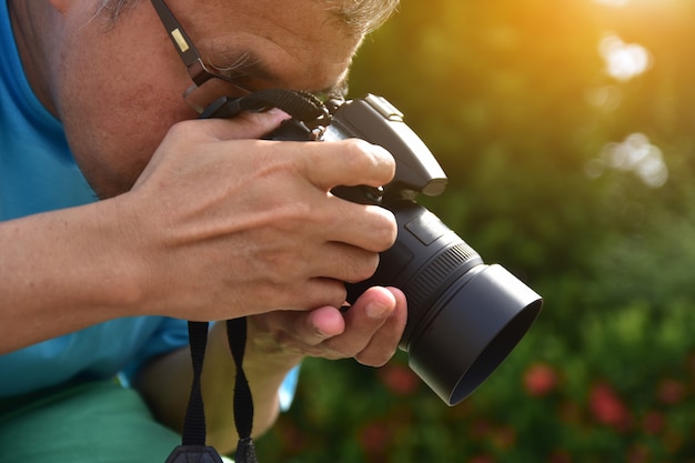 Macchina fotografica della tenuta dell&#39;uomo e fondo verde della natura della foglia