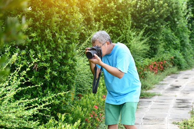 Macchina fotografica della tenuta dell&#39;uomo e fondo verde della natura della foglia