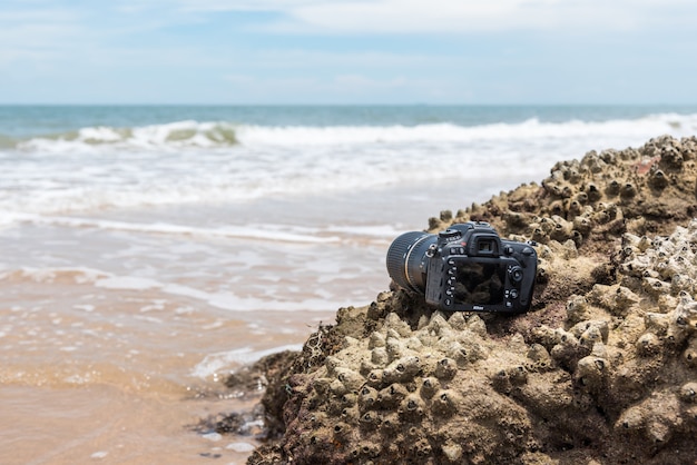 Macchina fotografica di DSLR sulla spiaggia bagnata dall&#39;onda del mare dell&#39;acqua