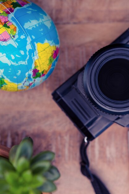 Macchina fotografica e globo di pianta in vaso sul tavolo