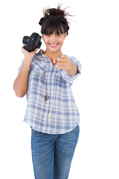 Macchina fotografica sorridente della tenuta della donna e indicare la sua barretta