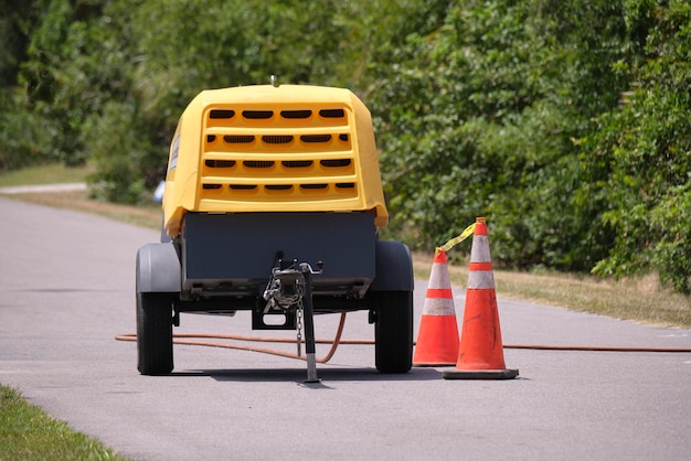 Macchina martello pneumatico giallo con rimorchio compressore sul cantiere stradale