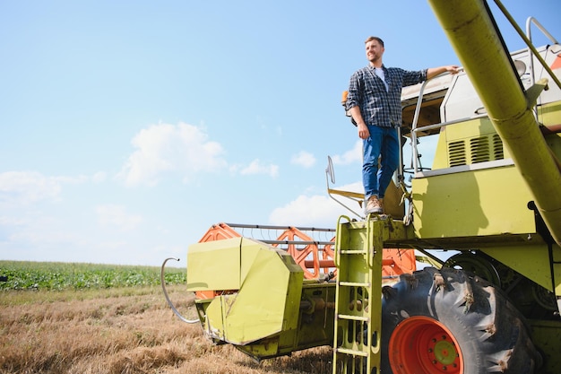 Macchina mietitrice conducente salendo in una cabina per raccogliere il suo campo di grano agricoltore che entra nella mietitrebbia su scala tenendo la ringhiera agronomo allevatore dopo il lavoro di raccolta