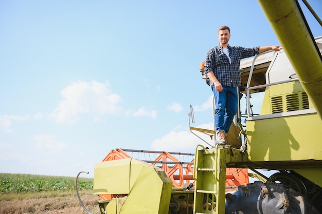 Macchina mietitrice conducente salendo in una cabina per raccogliere il suo campo di grano agricoltore che entra nella mietitrebbia su scala tenendo la ringhiera agronomo allevatore dopo il lavoro di raccolta