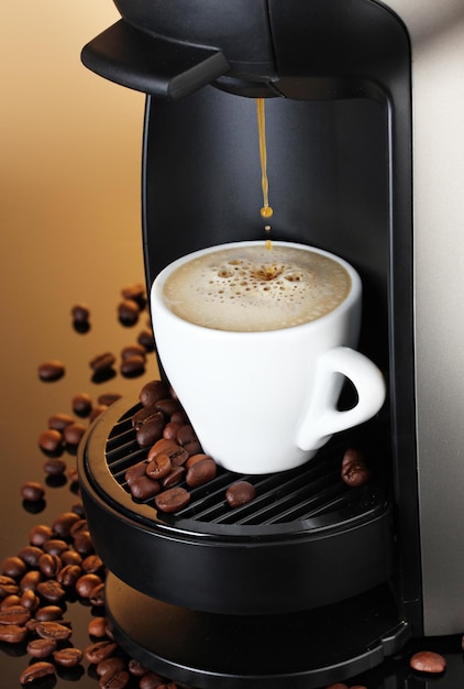 Macchina per caffè espresso versando il caffè in tazza su sfondo marrone