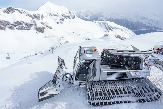 Macchina per la cura della neve sulla collina innevata pronta per la preparazione di piste da sci nelle Alpi svizzere