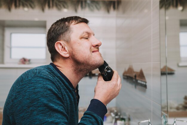 Macchina per rifinire la barba. regolabarba. un uomo si taglia la barba con un regolabarba.