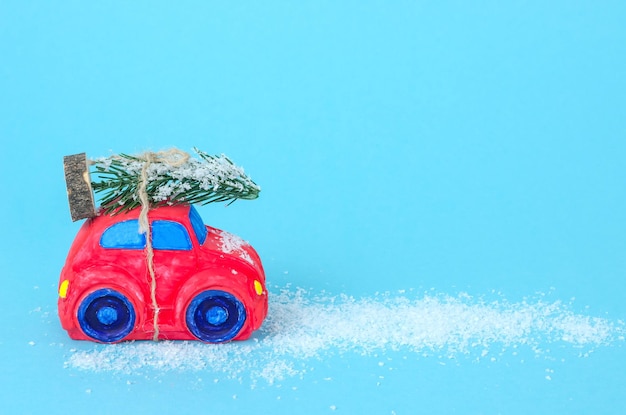 Macchina rossa con un albero di Natale su sfondo blu con neve con spazio per il testo