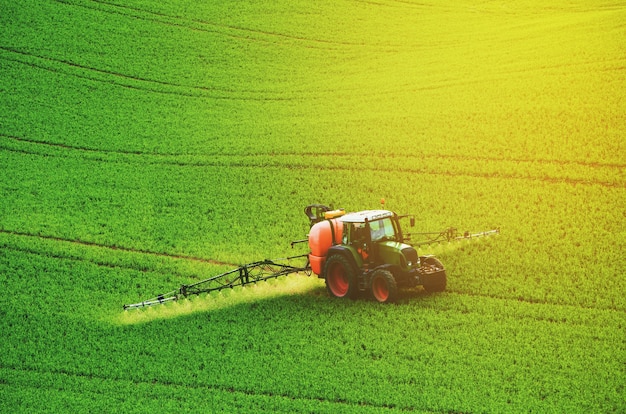 Macchine agricole che spruzzano insetticida sul campo verde, sfondo primaverile naturale agricolo stagionale