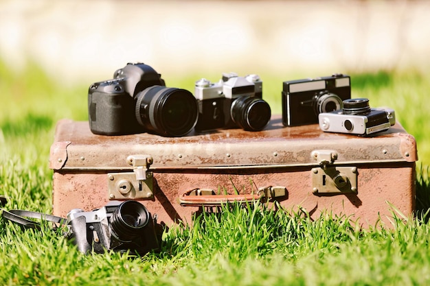 Macchine fotografiche moderne e vecchie sulla valigia all'aperto