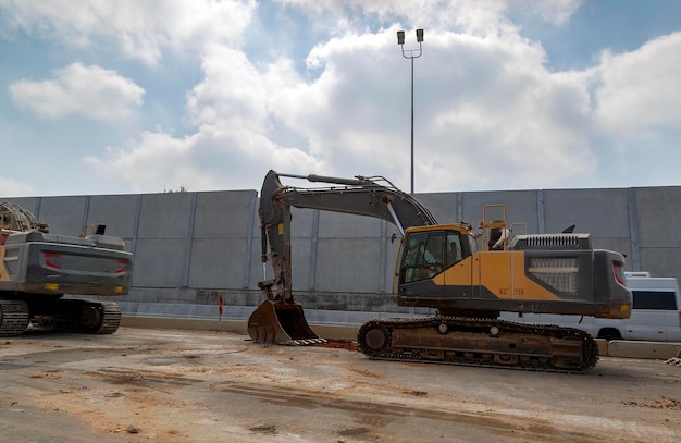 Macchine per la costruzione di strade sulla costruzione dell'autostrada sullo sfondo del cielo blu Escavatore con ruote grandi su strada nuova non ancora pronta Trattore agricolo lato stand sull'asfalto