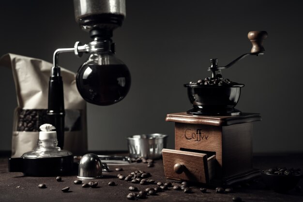 Macchinetta del caffè e macinacaffè giapponesi del sifone sul vecchio fondo del tavolo da cucina.