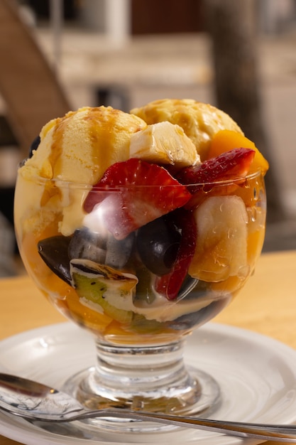 Macedonia di frutta con gelato in una tazza di vetro. Foto ravvicinata