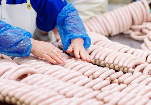 Macellai che trasformano le salsiccie alla fabbrica della carne.