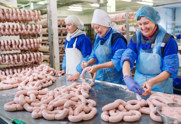 Macellai che trasformano le salsiccie alla fabbrica della carne.