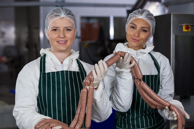 Macellai femminili che elaborano le salsiccie