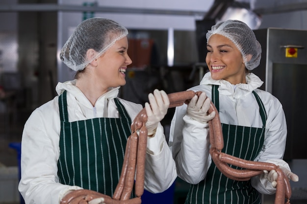 Macellai femminili che elaborano le salsiccie