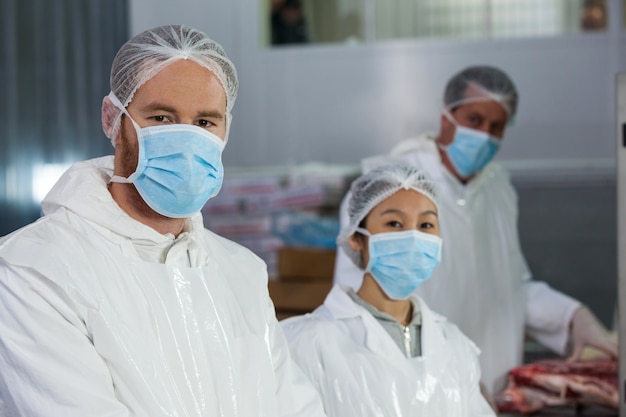 Macellai in indumenti da lavoro protettivi nella fabbrica di carne