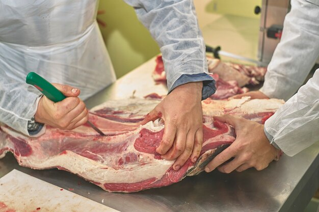 Macellaio al lavoro prepara i tagli di carne al banco e con gli attrezzi del mestiere