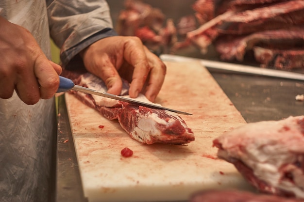 Macellaio che cerca di tirare o tagliare un pezzo di vitello in una macelleria.