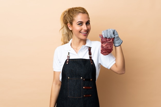 Macellaio donna che indossa un grembiule e che serve ridere carne tagliata fresca