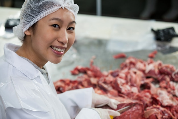 Macellaio femminile che taglia carne alla fabbrica di carne