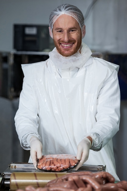 Macellaio maschio che pesa le salsiccie alla fabbrica della carne