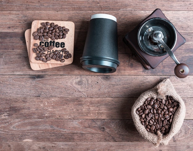 Macinacaffè, caffè beens in tela e carta nera cp su un tavolo di legno, piatto laici