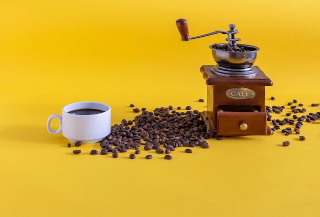 Macinacaffè manuale vintage con chicchi di caffè e una tazza