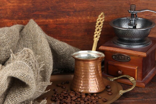 Macinacaffè turco e chicchi di caffè sul vassoio dorato su fondo di legno