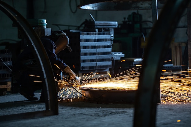 Macinatura elettrica su struttura in acciaio e saldatori con più scintille in fabbrica.