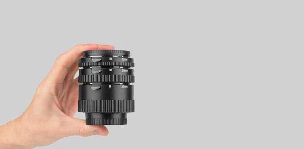 Macro anelli per una macchina fotografica in una mano maschile su uno spazio di copia sfondo grigio