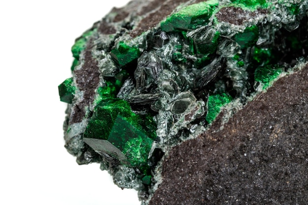 Macro pietra granato minerale Uvarovite in roccia su sfondo bianco