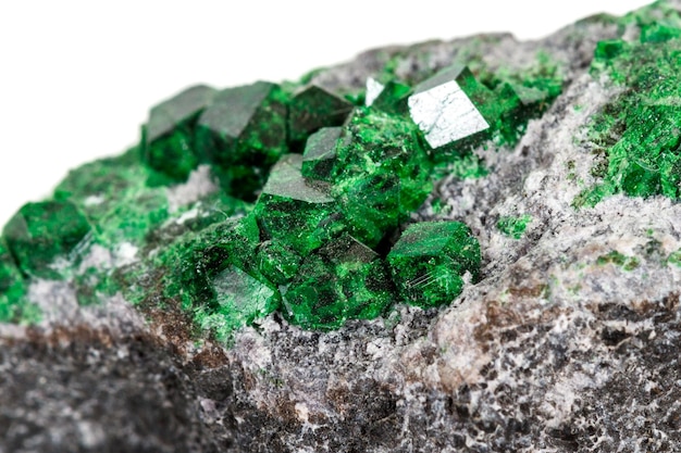 Macro pietra granato minerale Uvarovite in roccia su sfondo bianco